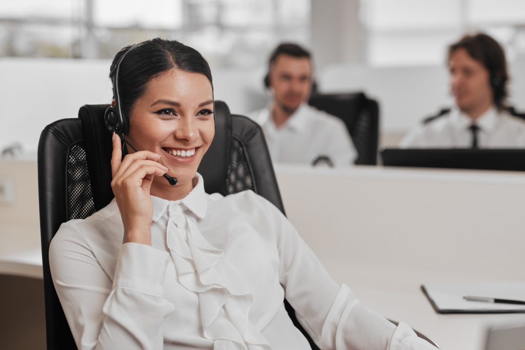 Lady with black hair smiling and talking into a headset